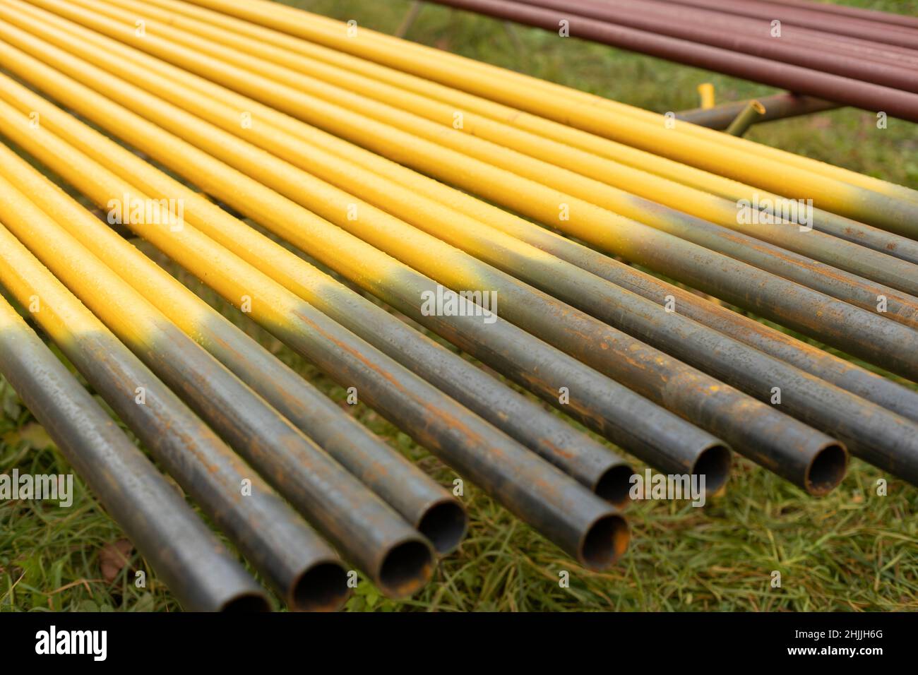 Rohre liegen in Reihe. Stahlteile. Gelbe Rohre zur Vergasung. Kommunikation in der Stadt. Stockfoto