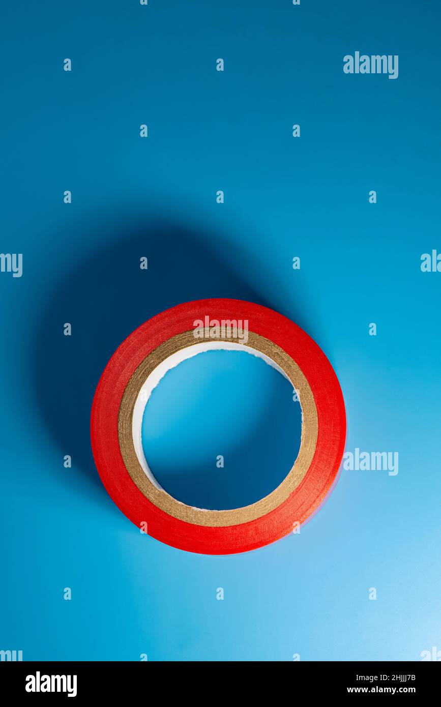 Isolierendes rotes Band liegt auf blauem Hintergrund. Hintergrund für das Design. Stockfoto