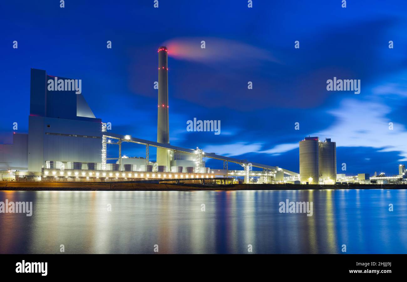 Großes beleuchtetes Kohlekraftwerk mit reflektierten Lichtern im Wasser eines Flusses Stockfoto