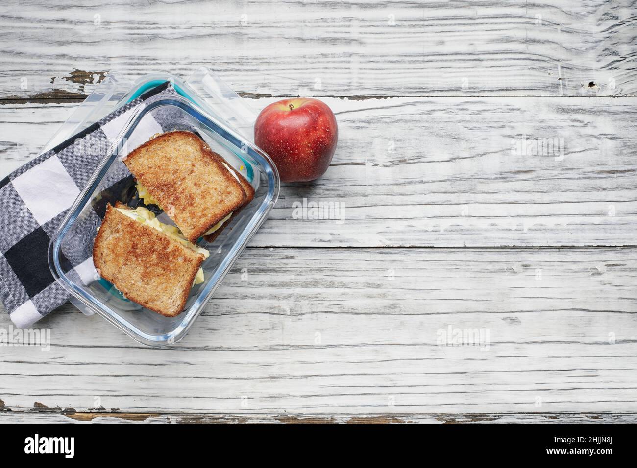 Lunchpaket mit frischem Apfel- und Hauseisalat-Sandwich mit geröstetem Weizenbrot in einem Glasbehälter. Gesunde vegetarische Ernährung Konzept. Stockfoto