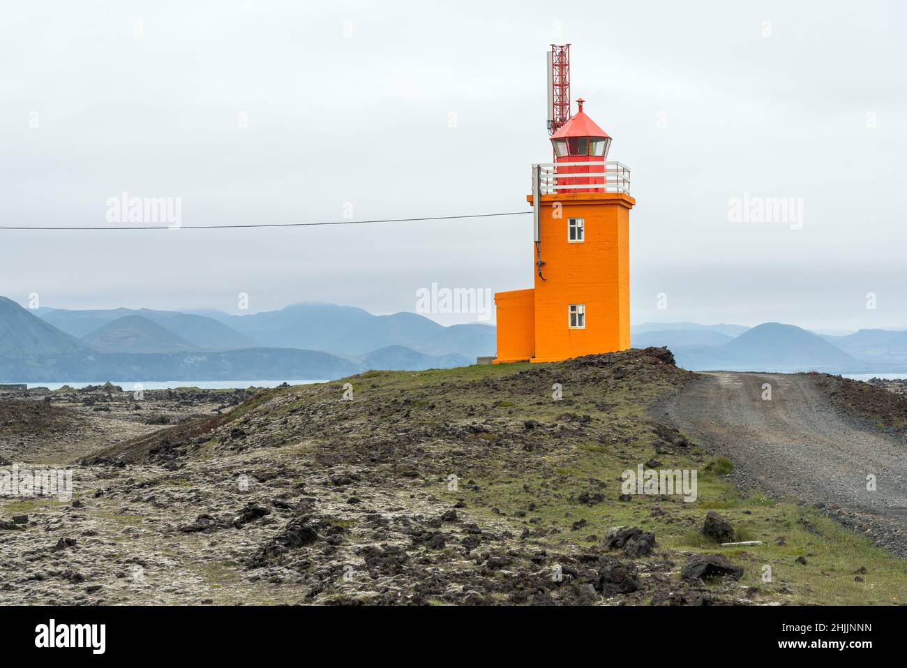 Oranger Leuchtturm an der Küste Islands an einem bewölkten und nebligen Sommertag Stockfoto