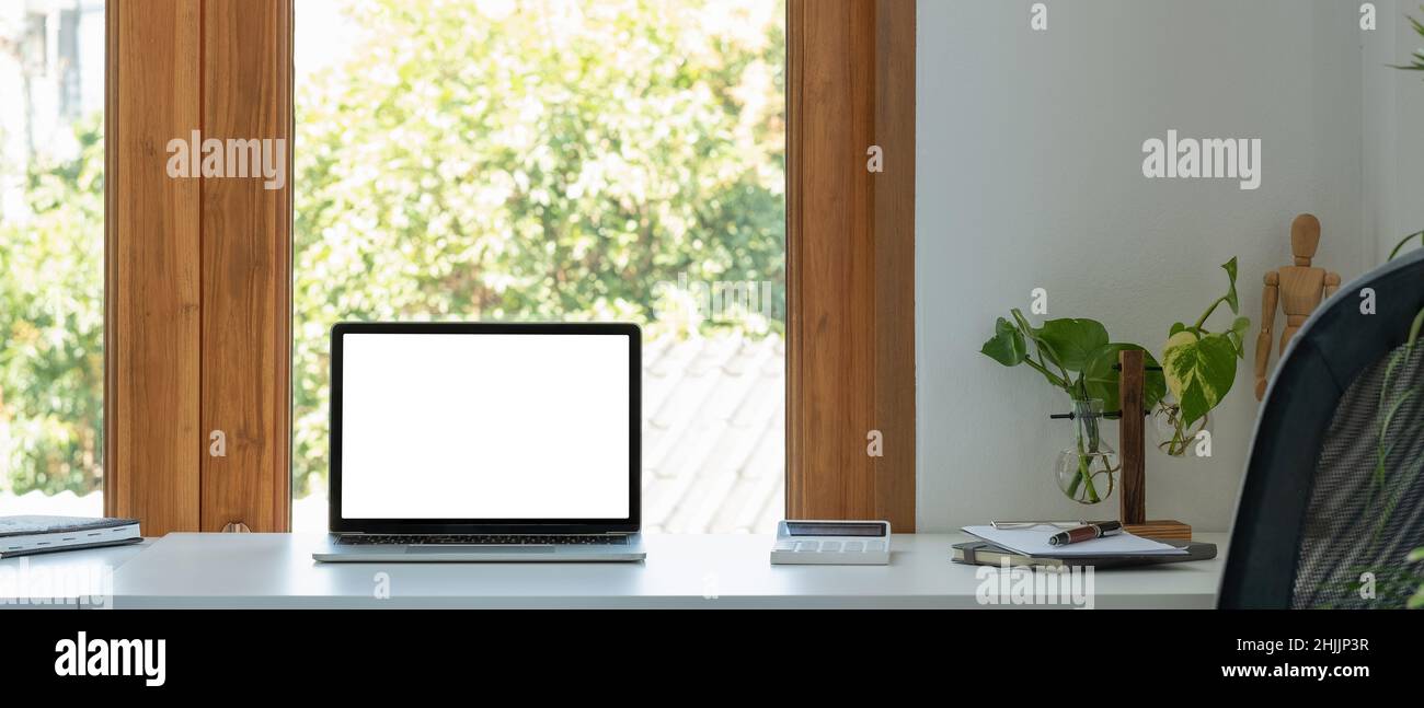 Laptop-Computer mit leerem Bildschirm in minimalem Büroraum mit Kalkulatpr, Dekorationen und Kopierraum. Stockfoto