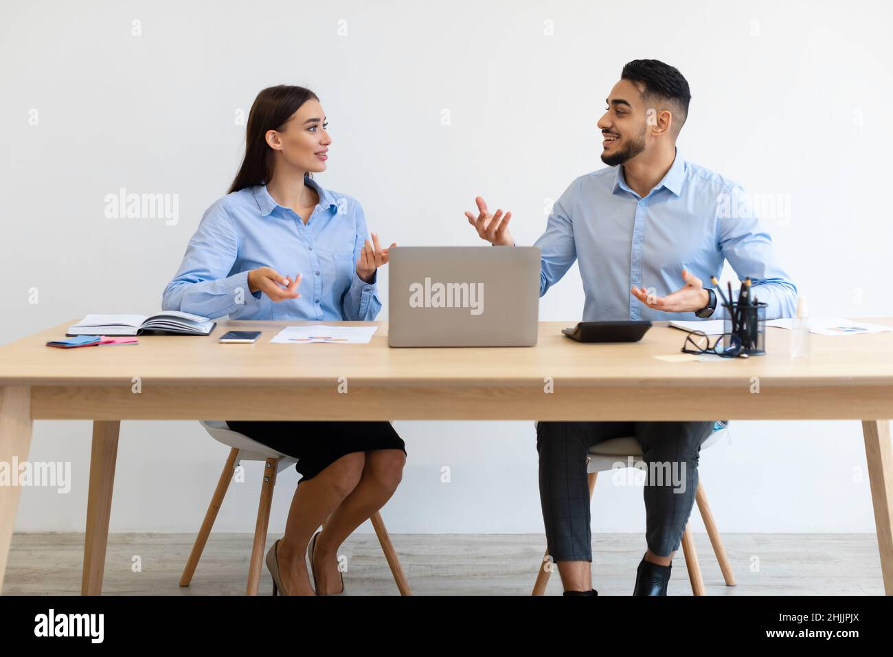 Porträt Lächelnder Kollegen, Die Am Schreibtisch Sitzen Und Sich Unterhalten Stockfoto