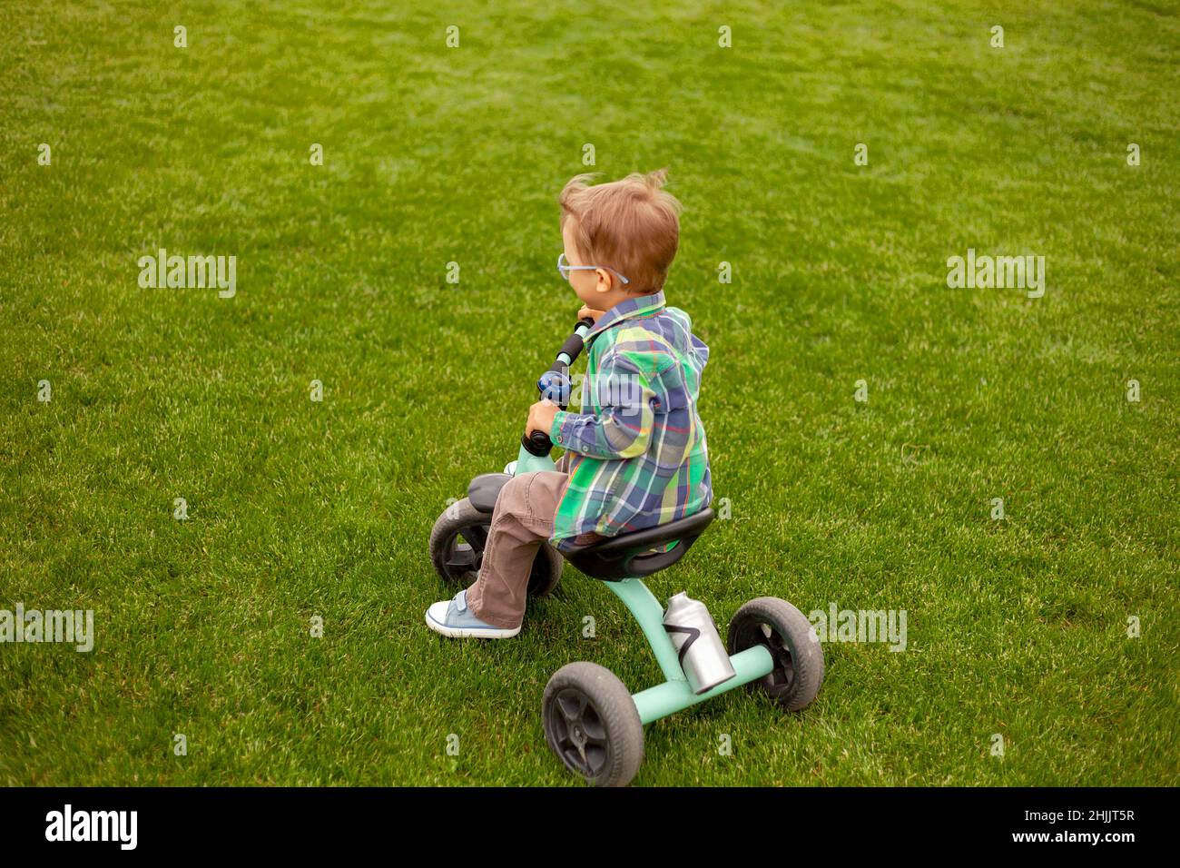 Kind fährt mit dem Fahrrad auf dem Rasen im Hinterhof Stockfoto