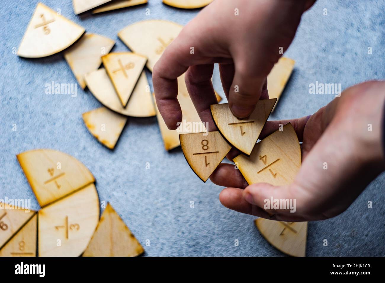 Nahaufnahme der Hand eines Kindes, das Bruchteile des Tortendiagramms mit Puzzleteilen hält Stockfoto