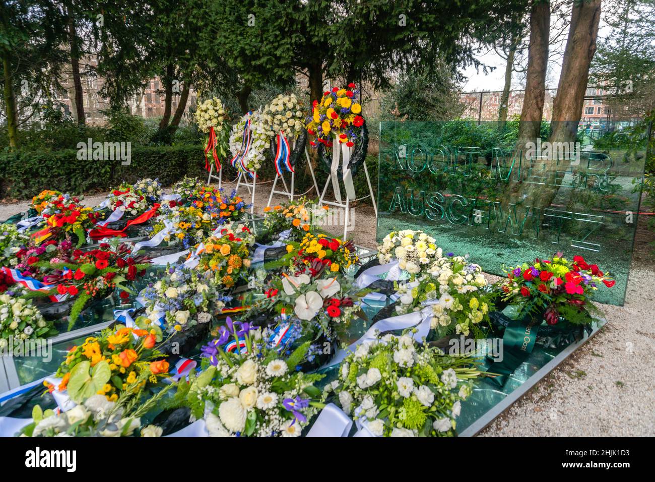 Amsterdam, Niederlande. 30. Januar 2022. Steht mit Blumenkränzen und dem Glasschirm mit den Worten 'Nooit Meer Auschwitz' am Auschwitz-Denkmal der zerbrochenen Spiegel, das am Nationalen Holocaust-Gedenktag mit Blumenkränzen bedeckt ist. Kredit: Steppeland/Alamy Live Nachrichten Stockfoto