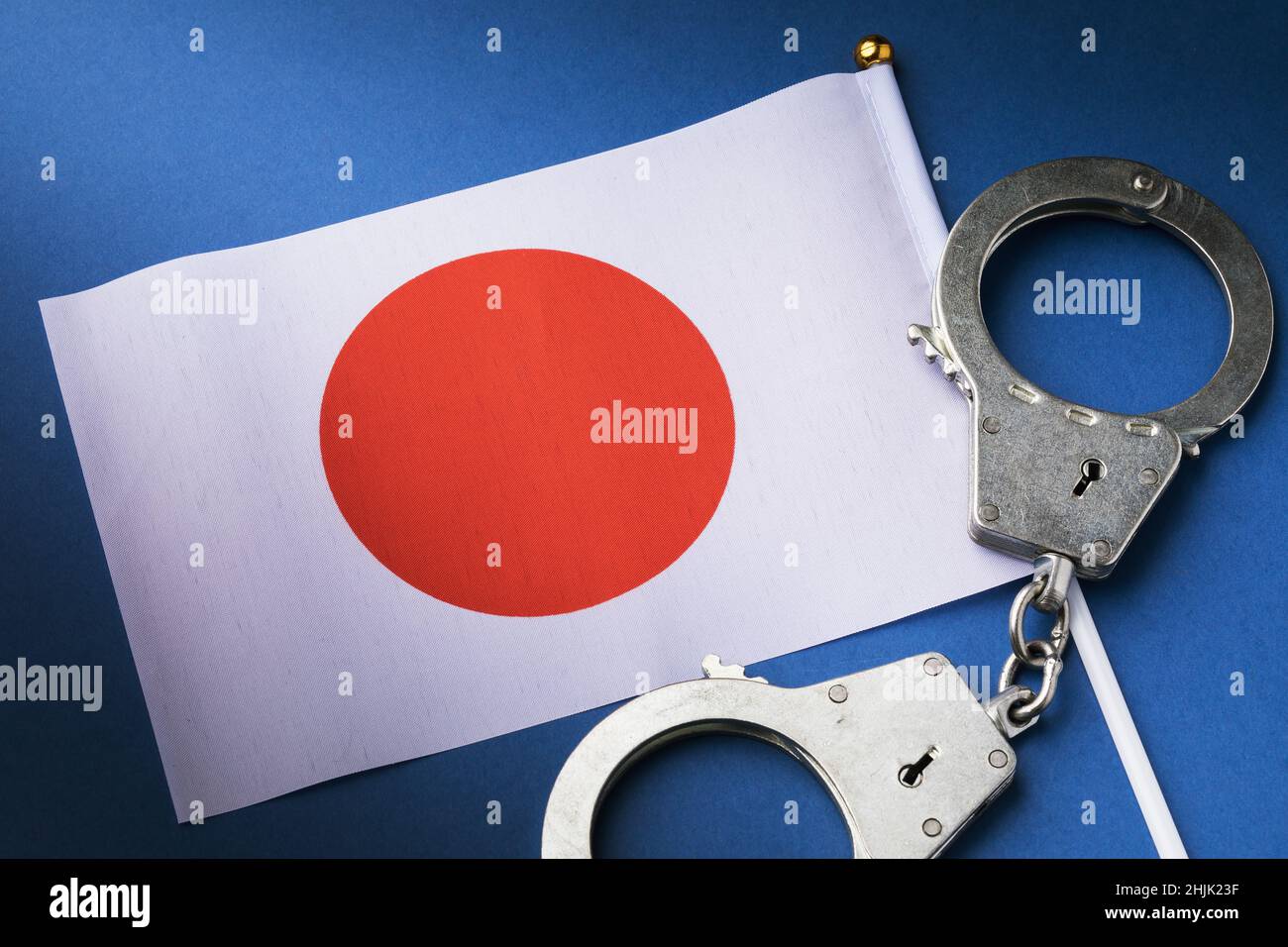 Flagge und Handschellen auf blauem Hintergrund, ein Konzept zum Thema Kriminalität in der japanischen Gesellschaft, Draufsicht Stockfoto