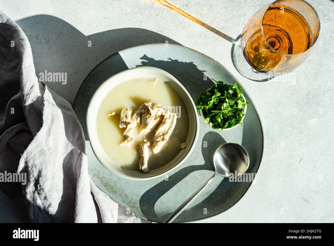 Blick von oben auf die traditionelle georgische Chikhirtma-Hühnersuppe mit einem Glas Wein Stockfoto