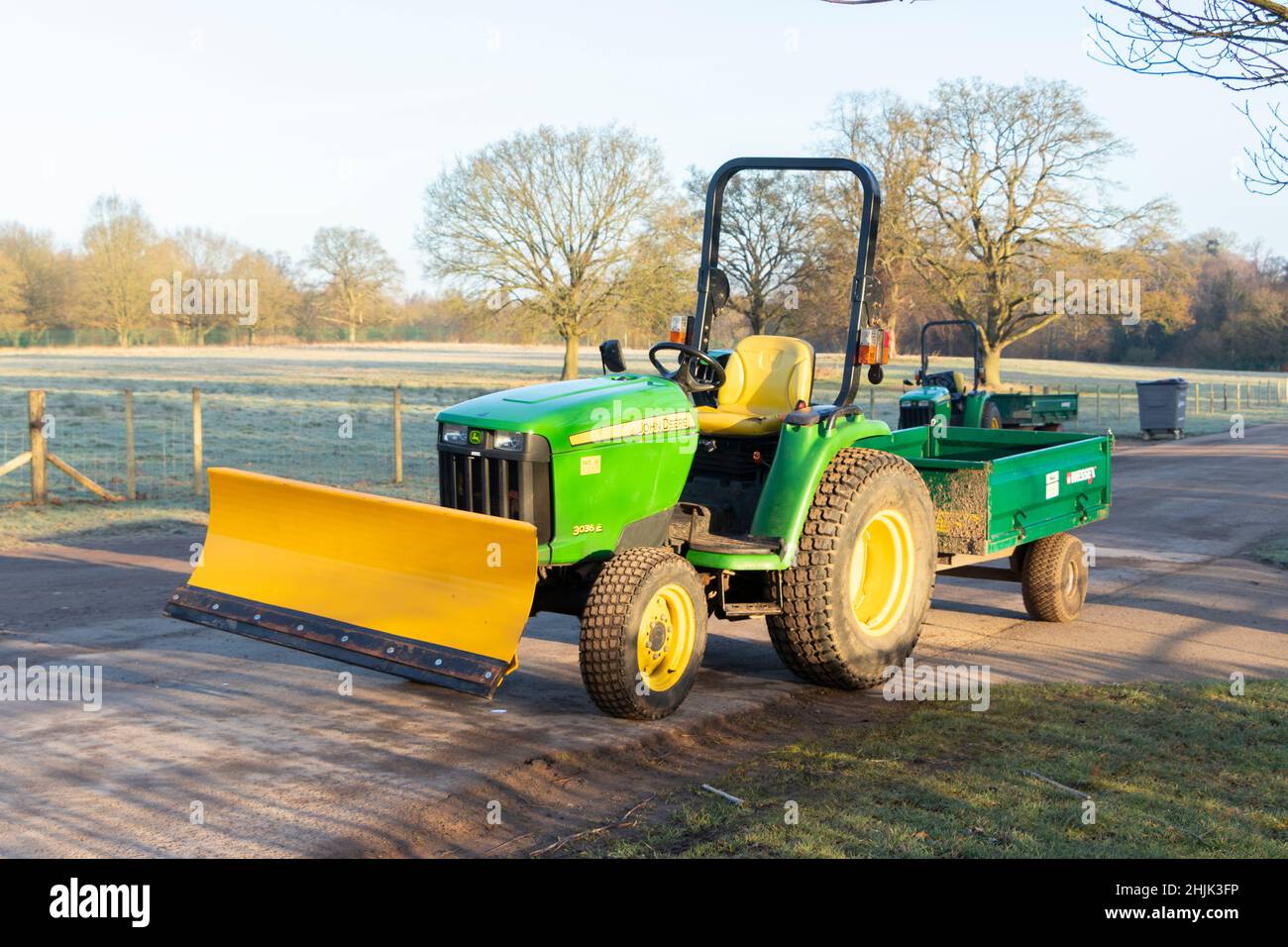 Kleiner grüner Traktor mit Klinge und Anhänger an einem kalten Wintermorgen in Trentham Gardens Stoke on Trent Stockfoto