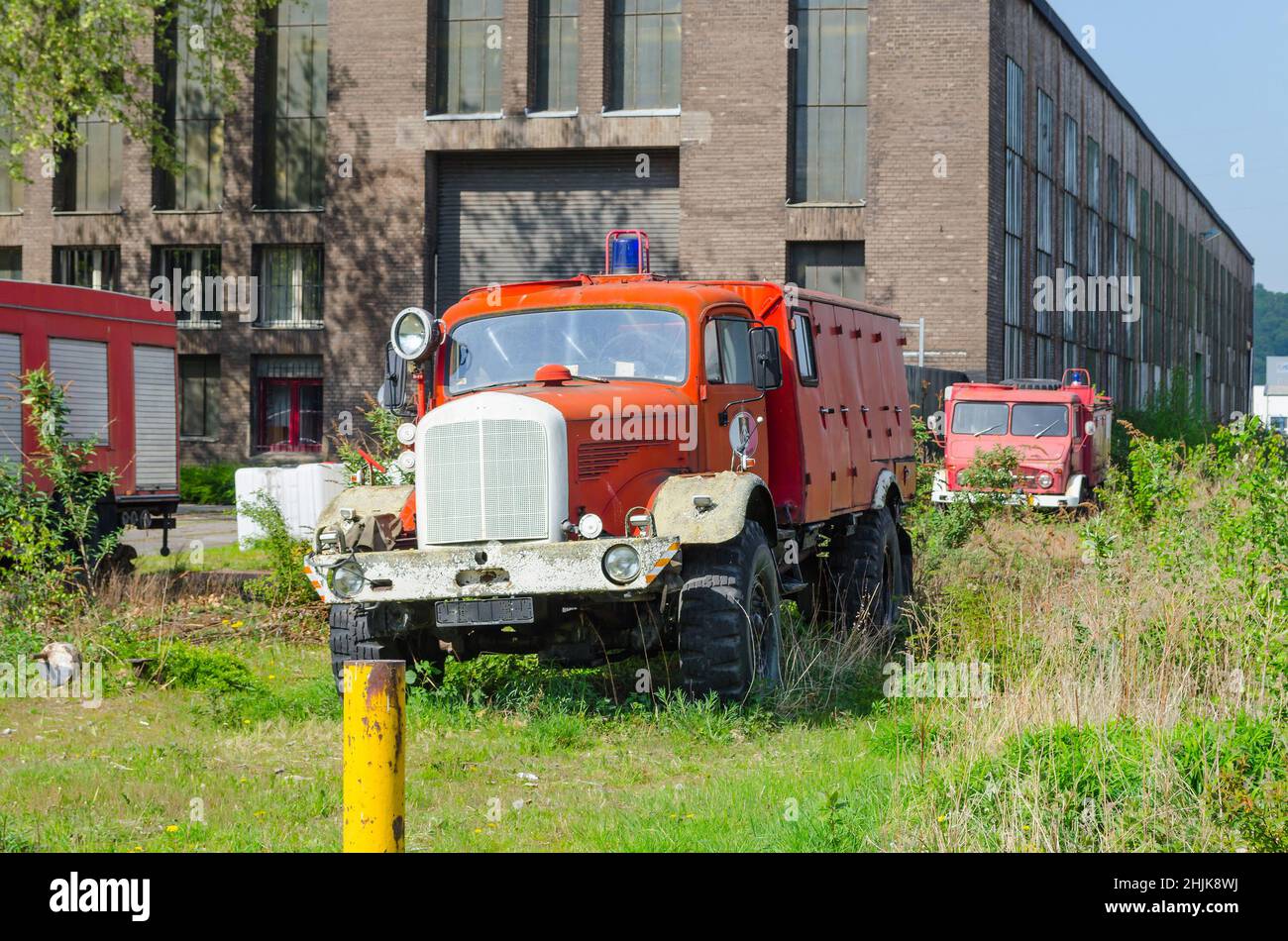 Alter verlassene Feuerwehrwagen auf einer Wiese vor einem alten Fabrikgebäude. Stockfoto