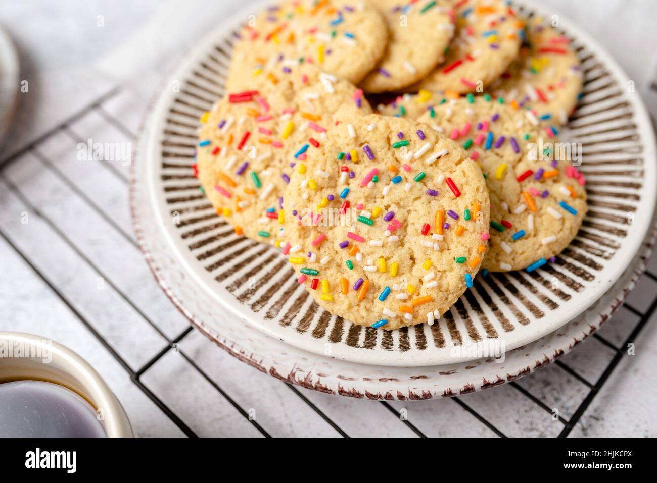 Zuckerkekse mit Streuseln, farbenfroher Kaffeegenuss. Frisch gebackene Dessertkekse. Stockfoto