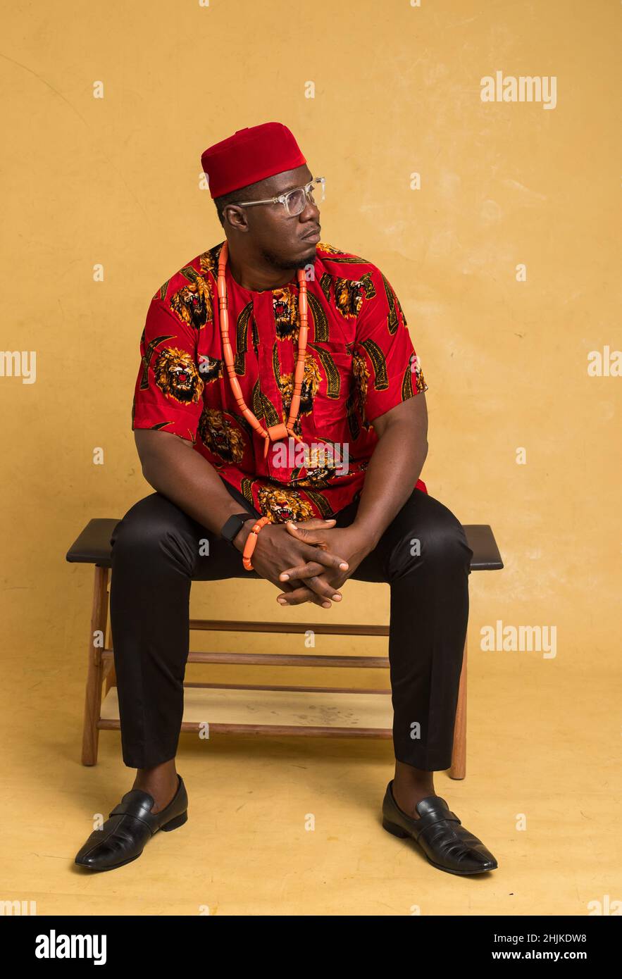 Igbo traditionell gekleideter Business man sitzt und schaut zur Seite Stockfoto