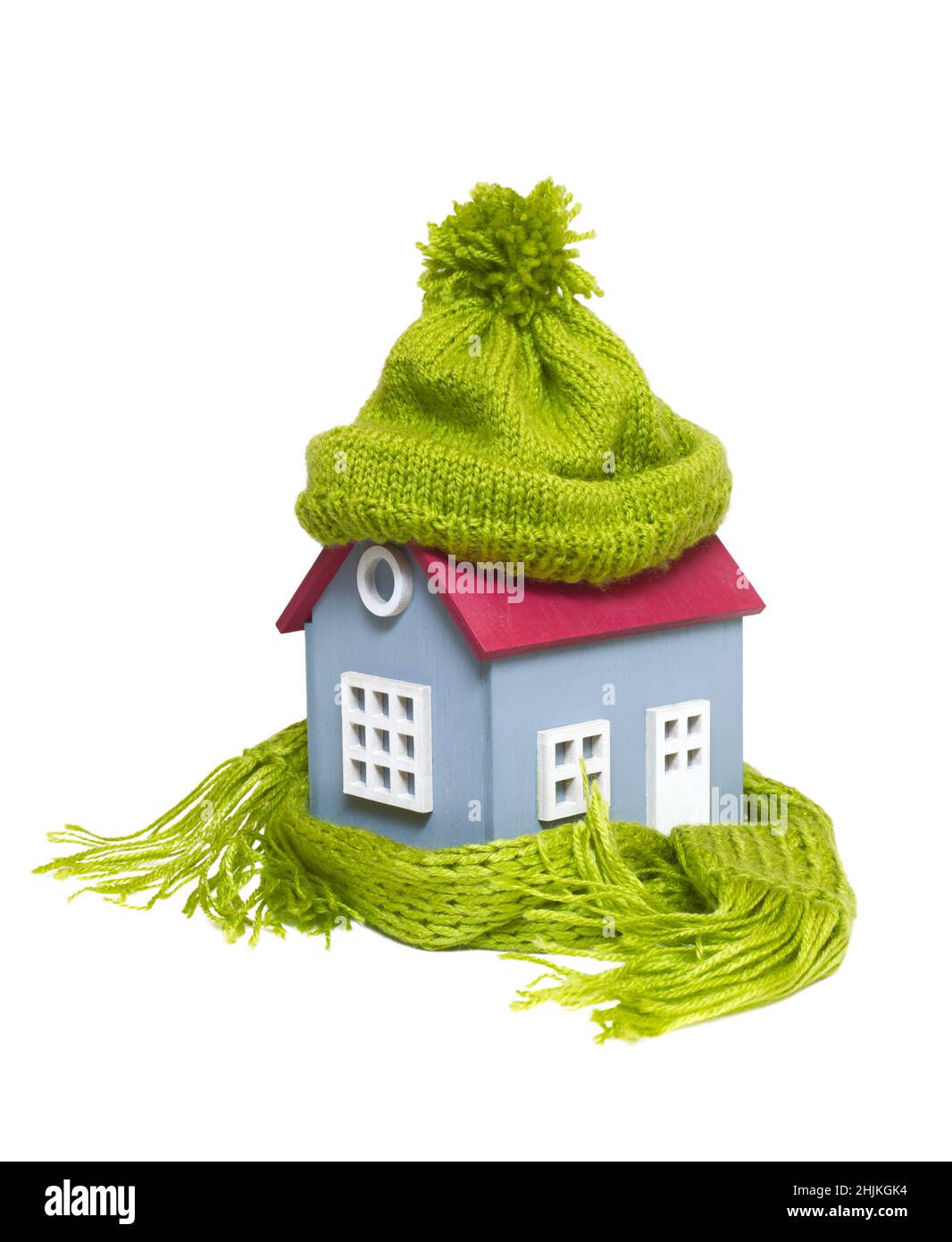 Konzeptionelles Miniaturmodell Haus mit grünem Wollhut und Schal, isoliert auf weißem Hintergrund Stockfoto
