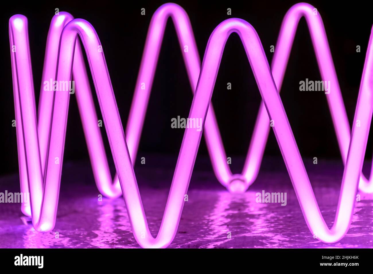 Beleuchtete Neonfigur in violetten Tönen Stockfoto