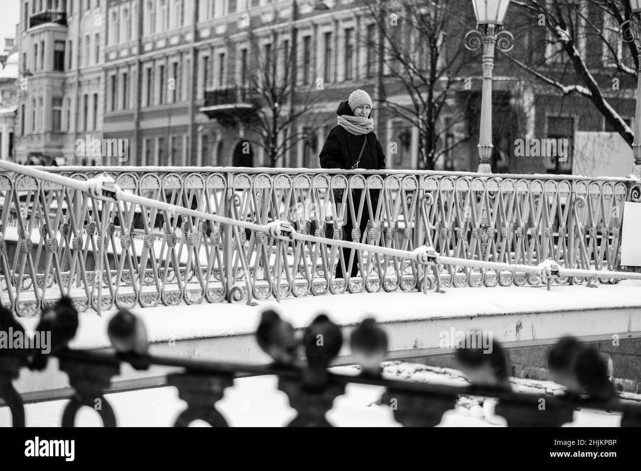 Frau, die auf einer Brücke über den Gribojedow-Kanal, St. Petersburg, Russland, steht. Schwarzweiß-Foto. Stockfoto