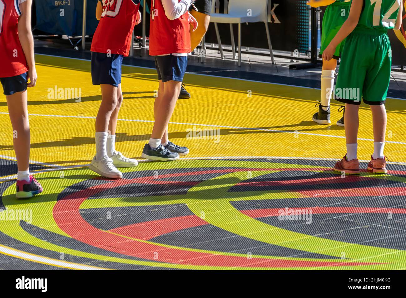 Füße von Kindern, die auf einem farbenfrohen Platz Basketball spielen Stockfoto