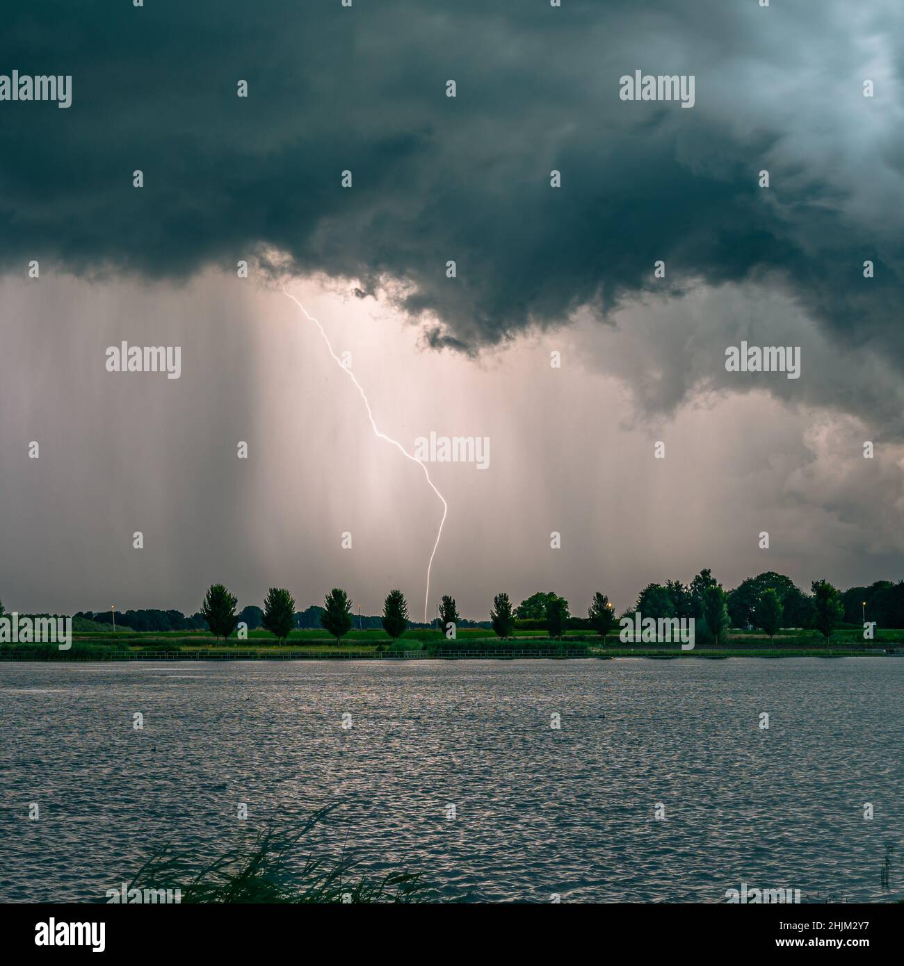 Positive Wolke zu Boden Blitzentladung in der Nähe eines Sees in der Dämmerung Stockfoto