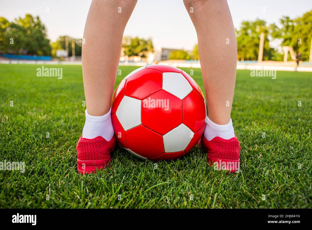 Ein Junge steht auf dem Fußballfeld eines Stadions mit einem Fußball zwischen seinen Beinen. Kinder spielen Fußball auf dem Rasen. Schulung oder Wettbewerb konz Stockfoto