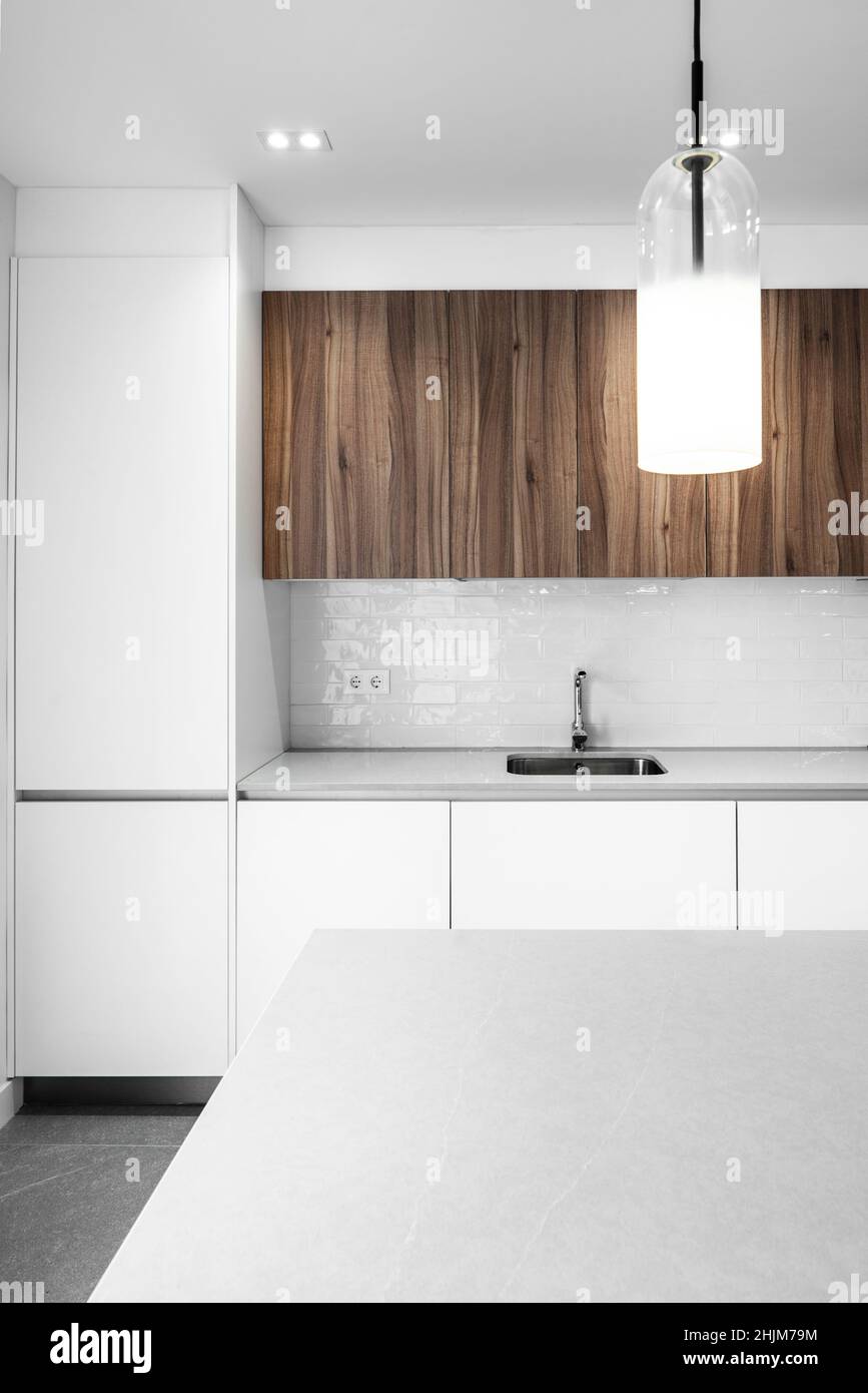 Wohnküche mit weißen Linien kombiniert mit hellem Wurzelholz und einem einzigen Waschbecken Stockfoto