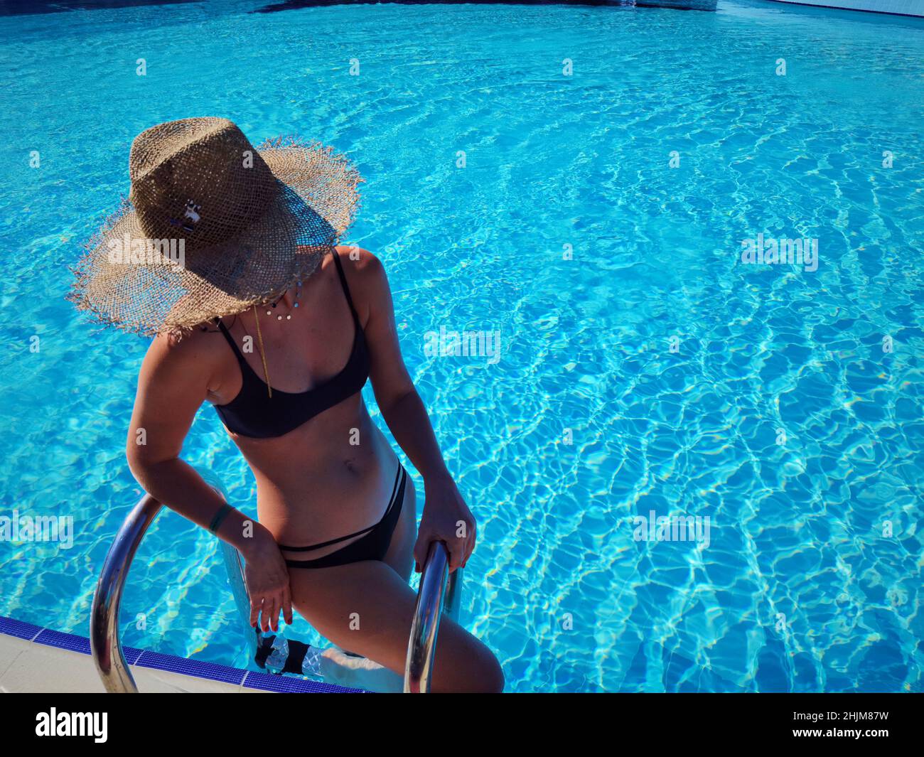 Porträt einer schönen Frau, die aus einem Schwimmbad. Schöne blonde Haare gebräunt weibliche Modell posiert von blauen Pool Wasser. Sommer im Freien Stockfoto