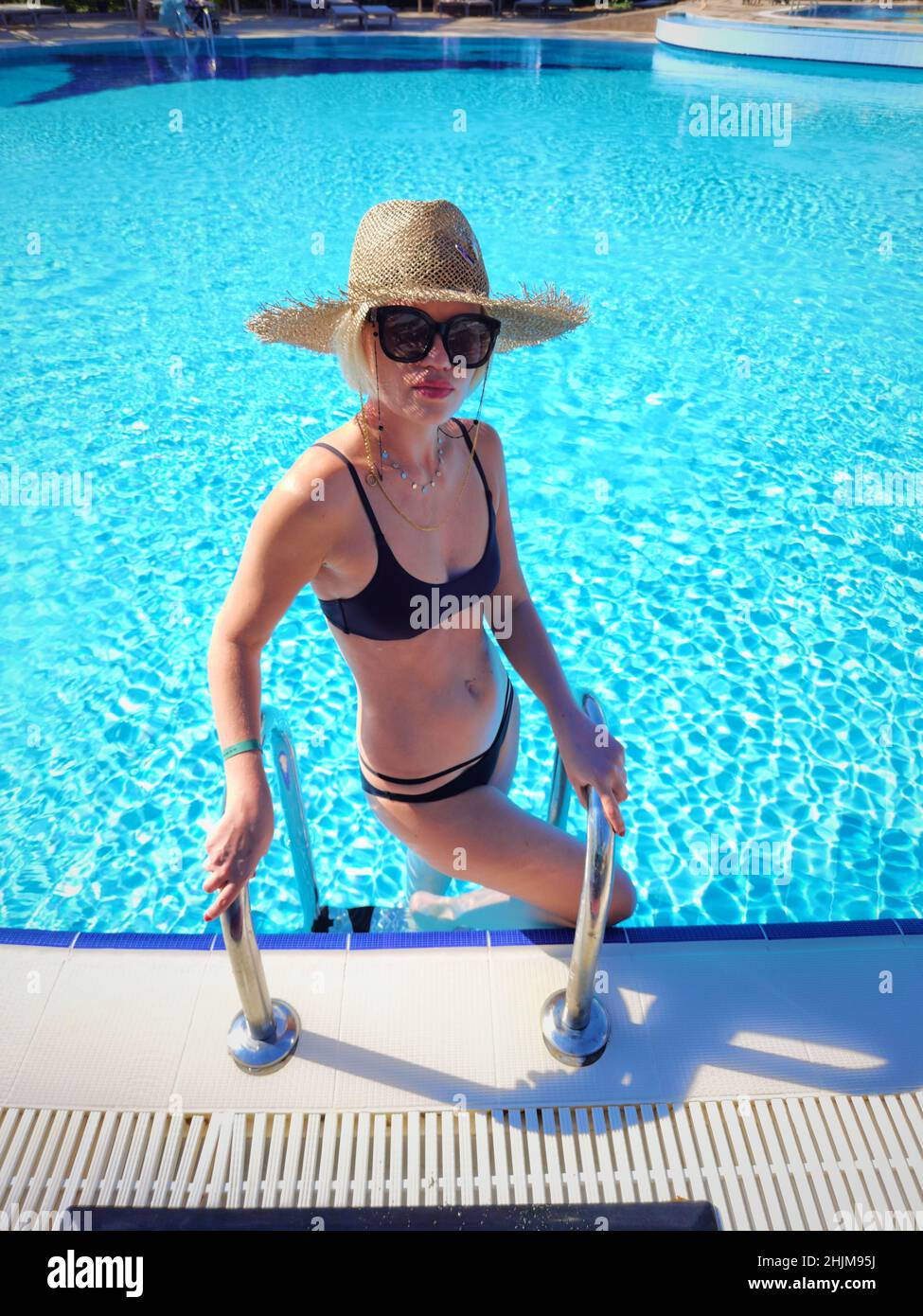Sexy Frau im Badeanzug ist im Schwimmbad entspannen. Wunderschöne Frau trägt Strohhut und entspannen Sie sich in der Sonne am Pool während der Sommerferien im Resort Stockfoto