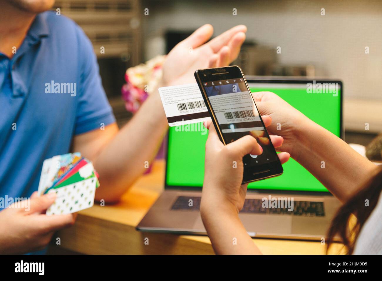 Verkaufsassistent scannt einen Barcode einer Karte mit einem Smartphone Stockfoto