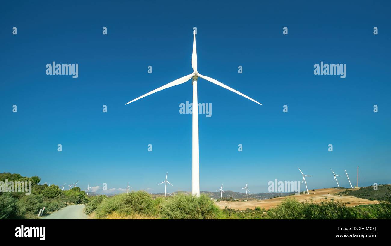 Ein riesiger Windgenerator vor dem Oreites-Windpark in Zypern gegen klaren blauen Himmel. Panorama-Landschaft mit Weitwinkelobjektiv dramatische Verzerrung Stockfoto