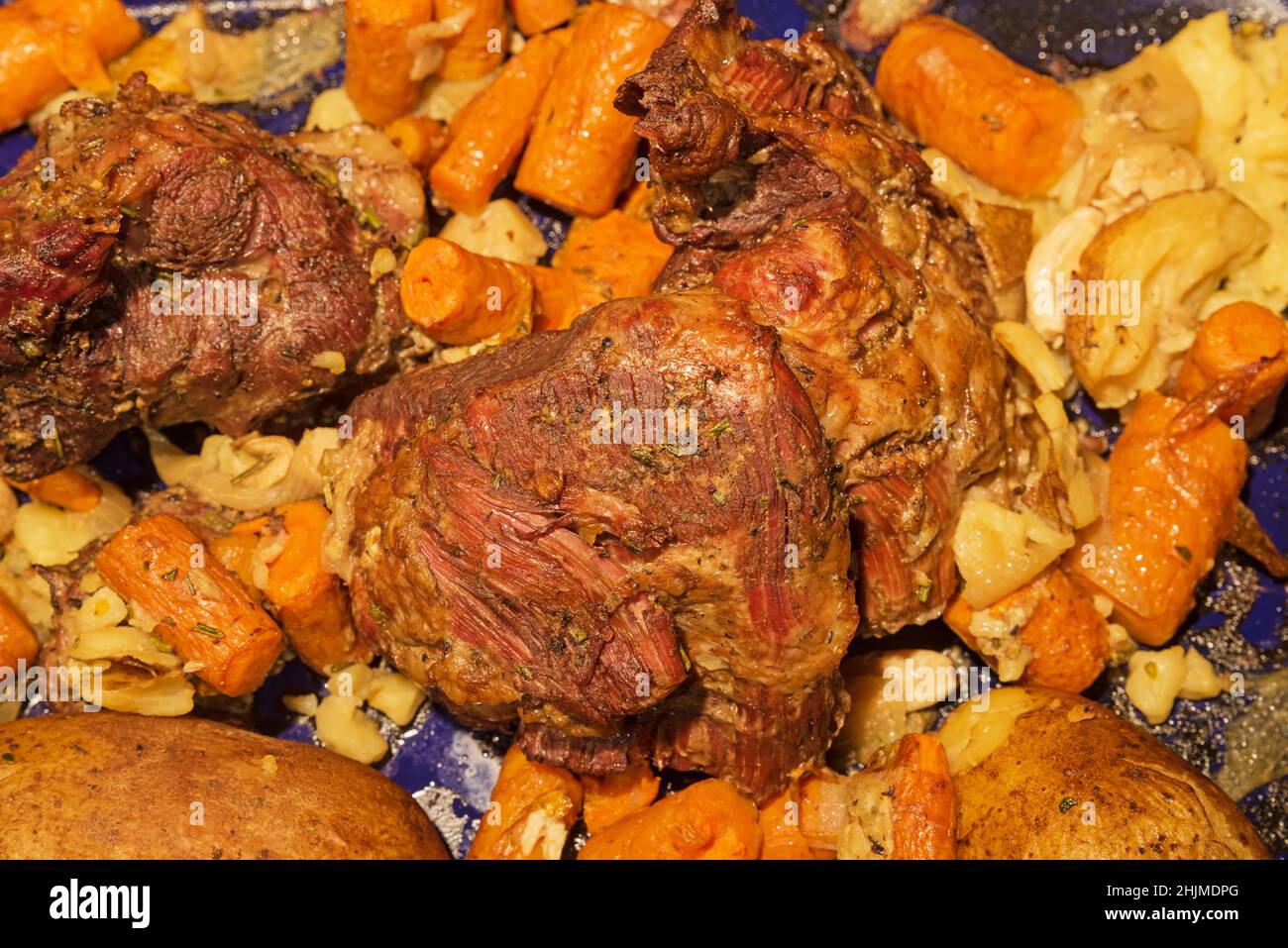 Ohne Knochen gebratenes Lammbein mit Kartoffeln und Karotten Stockfoto