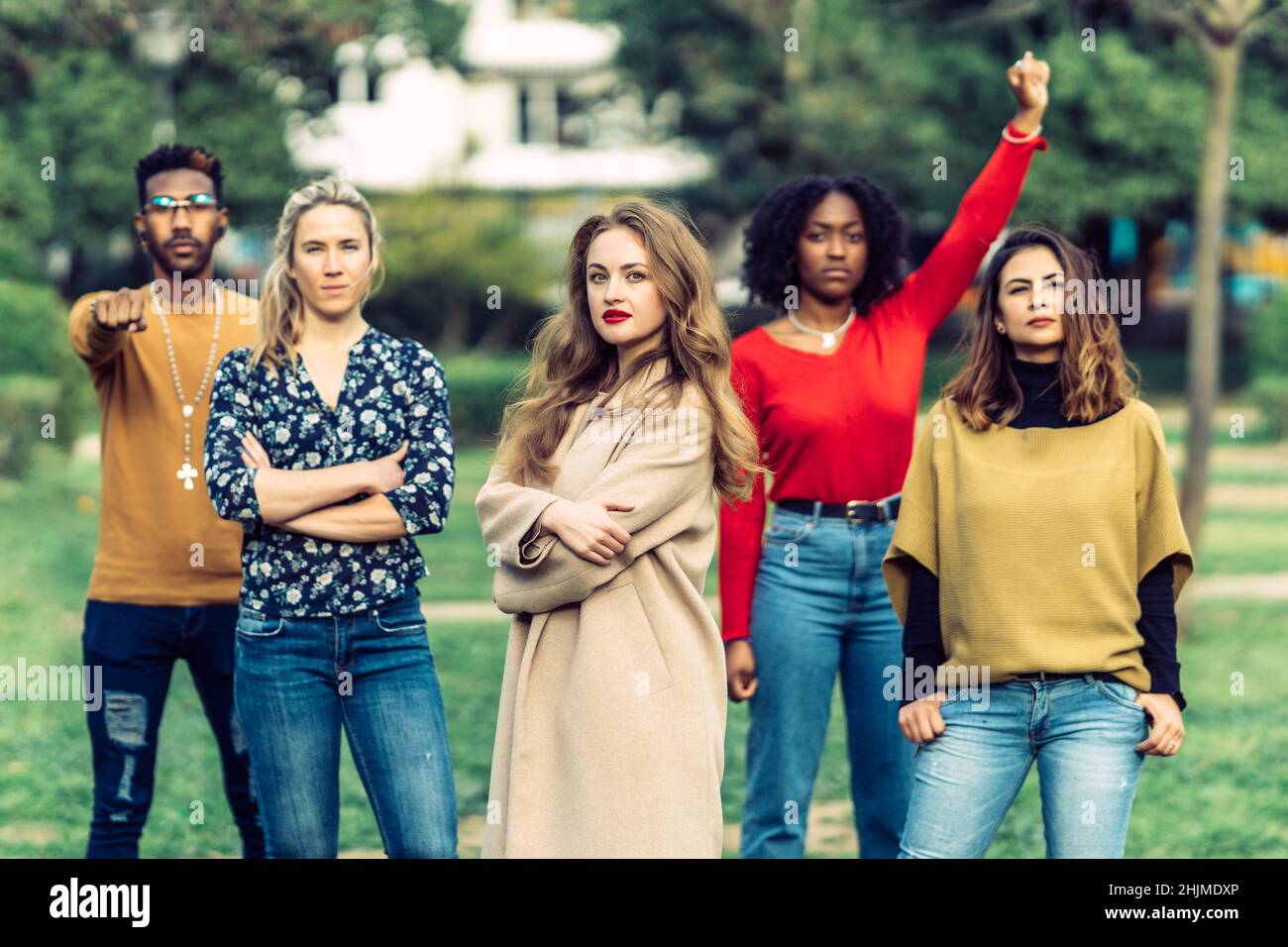Die junge blonde Frau, die einen Mantel trägt, blickt vor 4 Menschen intensiv auf die Kamera. Stockfoto