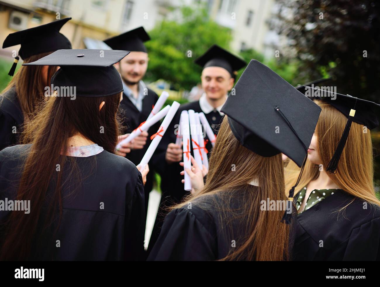 Gruppe von Hochschulabsolventen in Studentenroben oder Mantel und quadratische Hüte bei der Abschlussfeier halten College-Abschlusszeugnisse in ihren Stockfoto