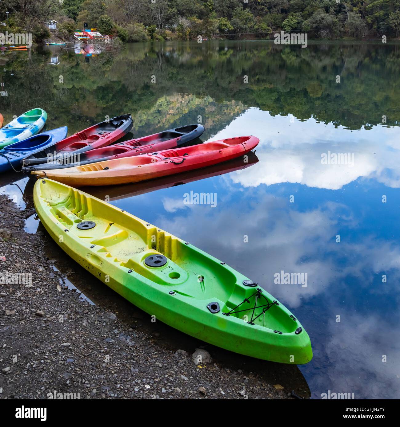 Bunte Boote am Ufer eines Sees mit der Spiegelung von Himmel und Hügeln Stockfoto