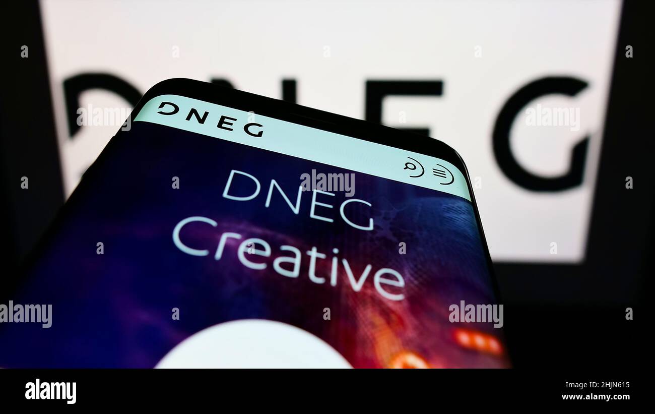 Mobiltelefon mit Website des britischen Visual Effects-Unternehmens DNEG plc auf dem Bildschirm vor dem Unternehmenslogo. Konzentrieren Sie sich auf die obere linke Seite des Telefondisplays. Stockfoto