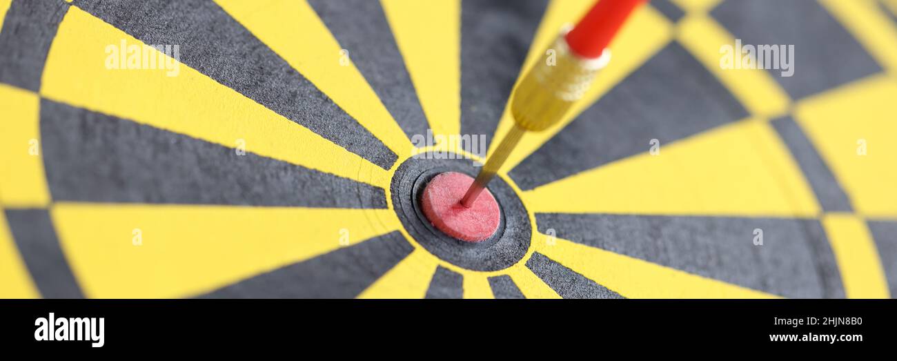 Pfeil in der Mitte der gelb-schwarzen Dartscheibe Nahaufnahme Stockfoto