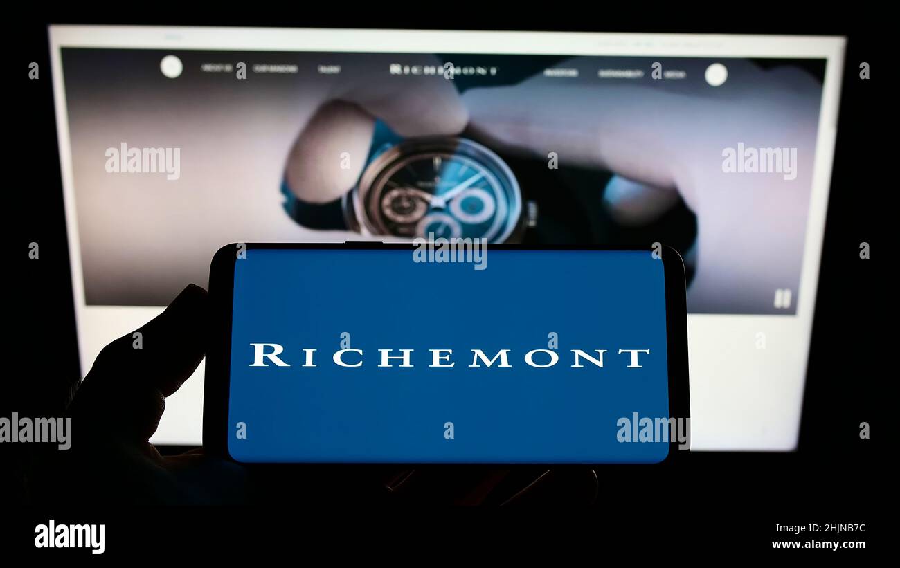 Person, die Smartphone mit Logo der Schweizer Compagnie Financiere Richemont S.A. auf dem Bildschirm vor der Website hält. Konzentrieren Sie sich auf die Telefonanzeige. Stockfoto