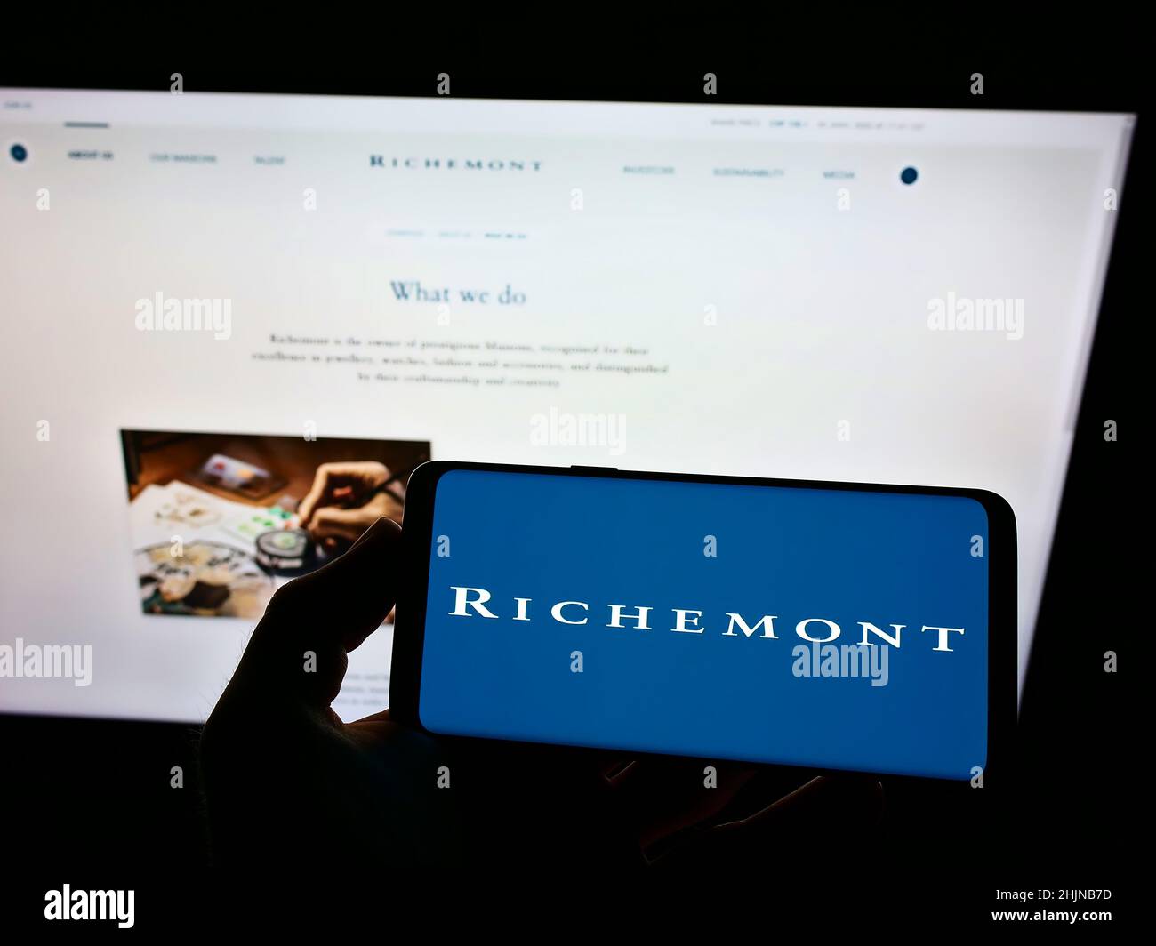 Person mit Mobiltelefon und Logo der Schweizer Compagnie Financiere Richemont SA auf dem Bildschirm vor der Webseite. Konzentrieren Sie sich auf die Telefonanzeige. Stockfoto