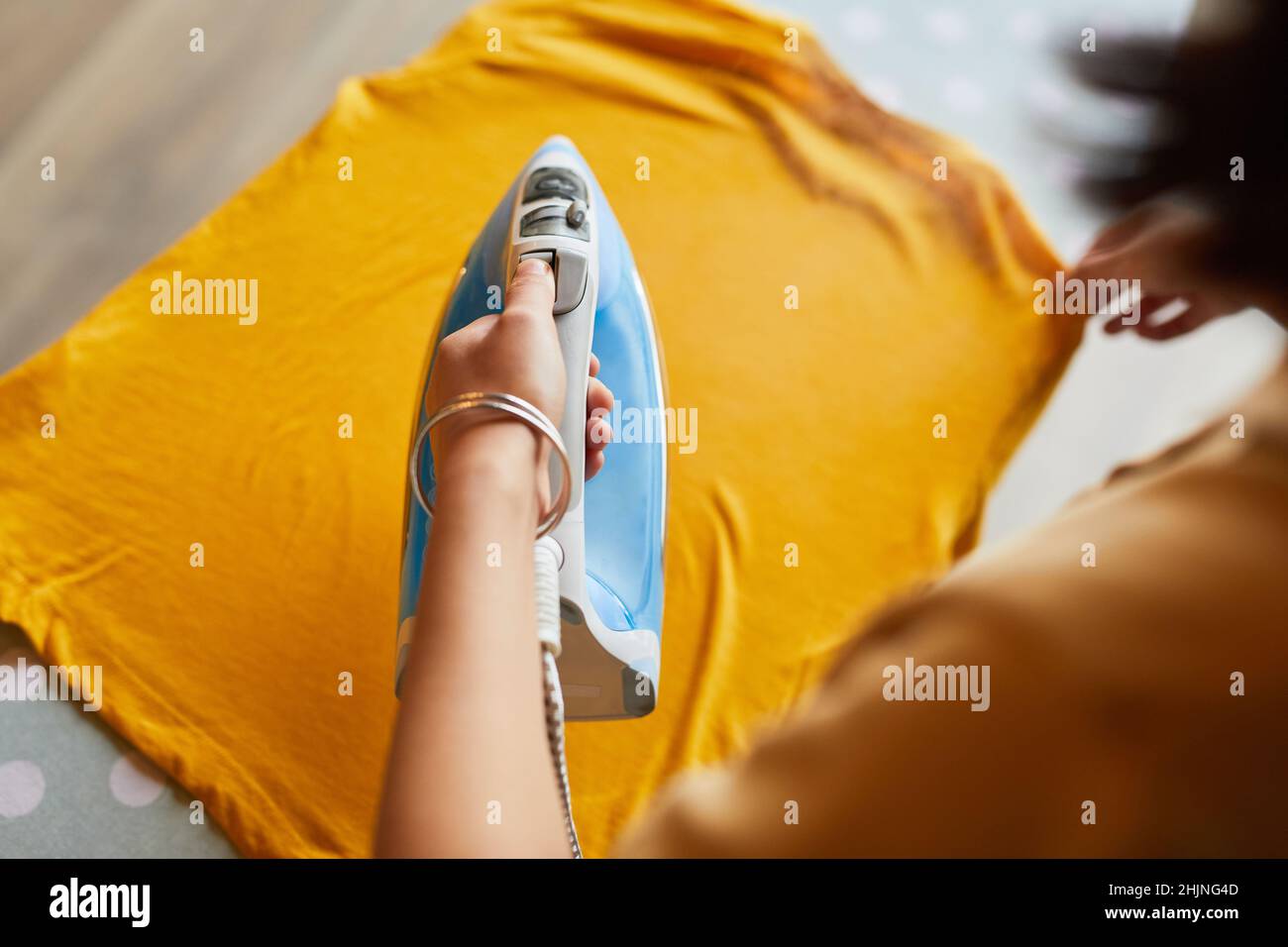 Nahaufnahme einer jungen Frau, die zu Hause Kleidung bügelt und Hausarbeiten erledigt, Platz zum Kopieren Stockfoto