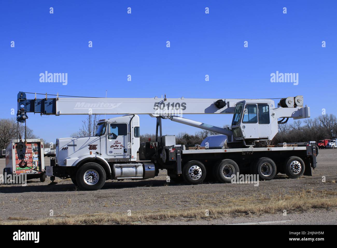 Eine Nahaufnahme mit einem ausziehbaren Kran auf einem Lastwagen mit blauem Himmel auf einem Parkplatz Stockfoto