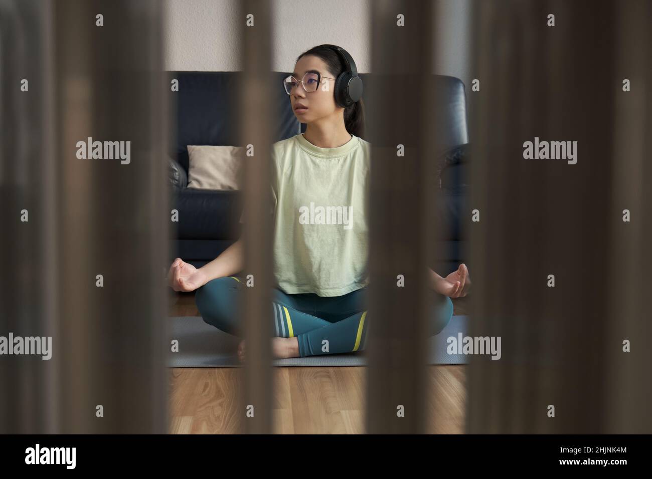 Junge asiatische Frau hört entspannende Musik und meditiert dabei die einfache Pose. Stockfoto