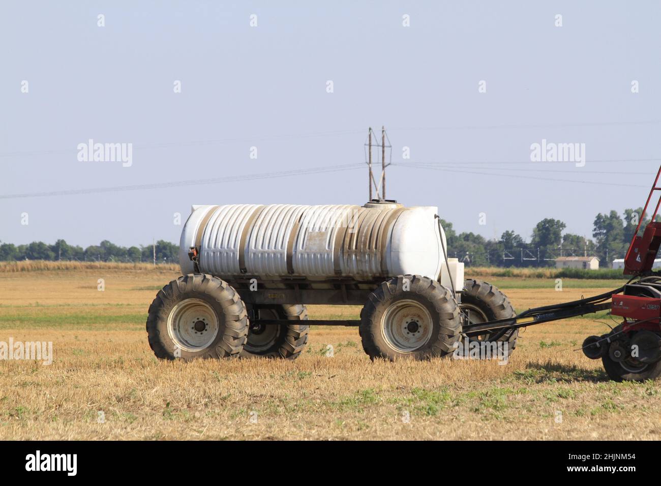 Ein Case International Traktor auf einem Feld mit Sprühgeräten auf der Rückseite mit blauem Himmel in Kansas im Land. Stockfoto
