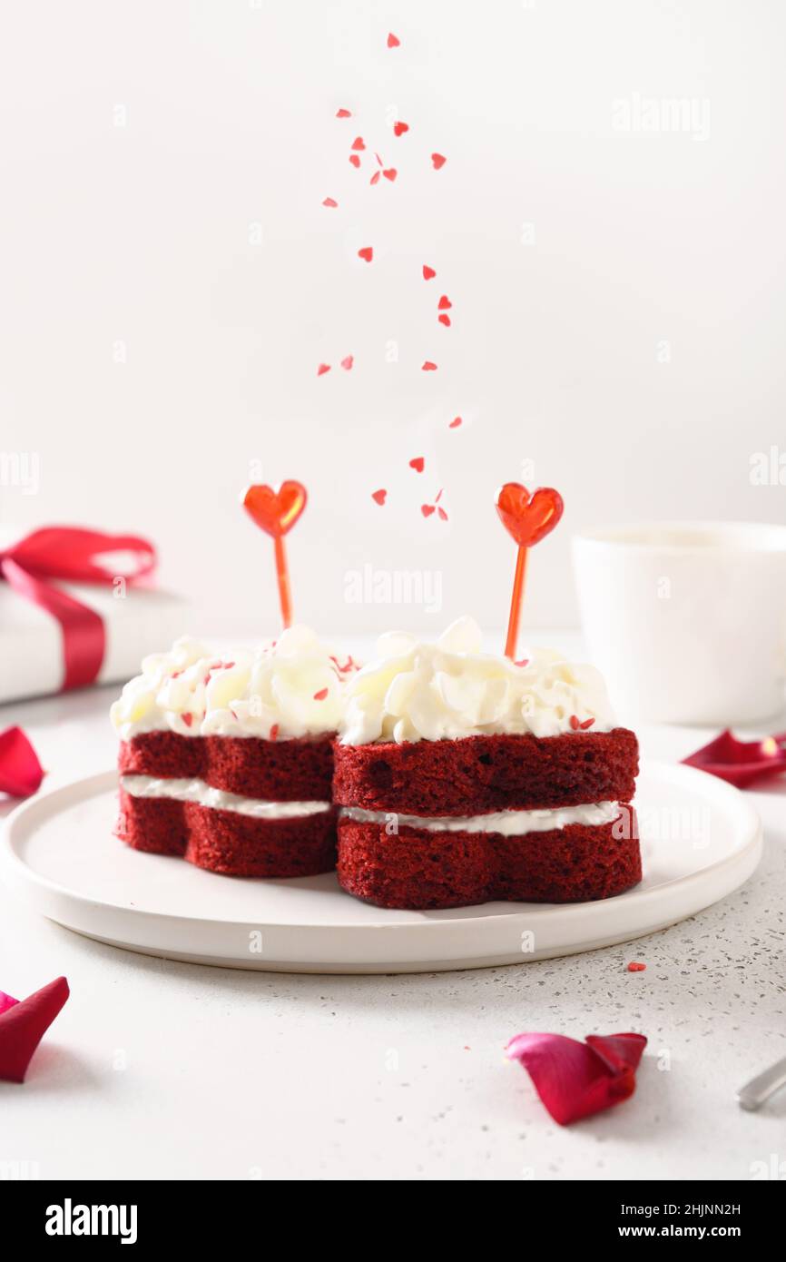 Zwei rote Samtkuchen und Streuseln als Herzen für den Valentinstag. Leckeres Dessert. Vertikales Format. Nahaufnahme. Stockfoto