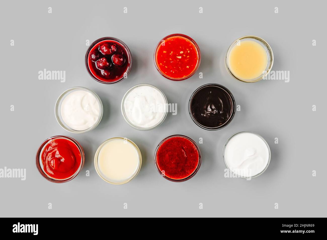 Verschiedene Saucen in kleinen Soßenschalen auf grauem Hintergrund. Draufsicht. Stockfoto