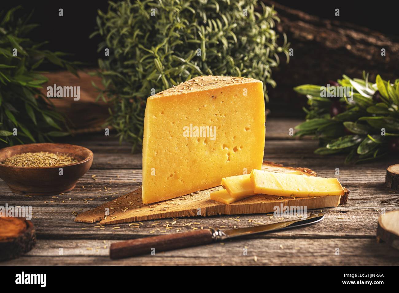 Dreieckige Käsescheibe mit Rosmarin auf Holzschneidebrett Stockfoto