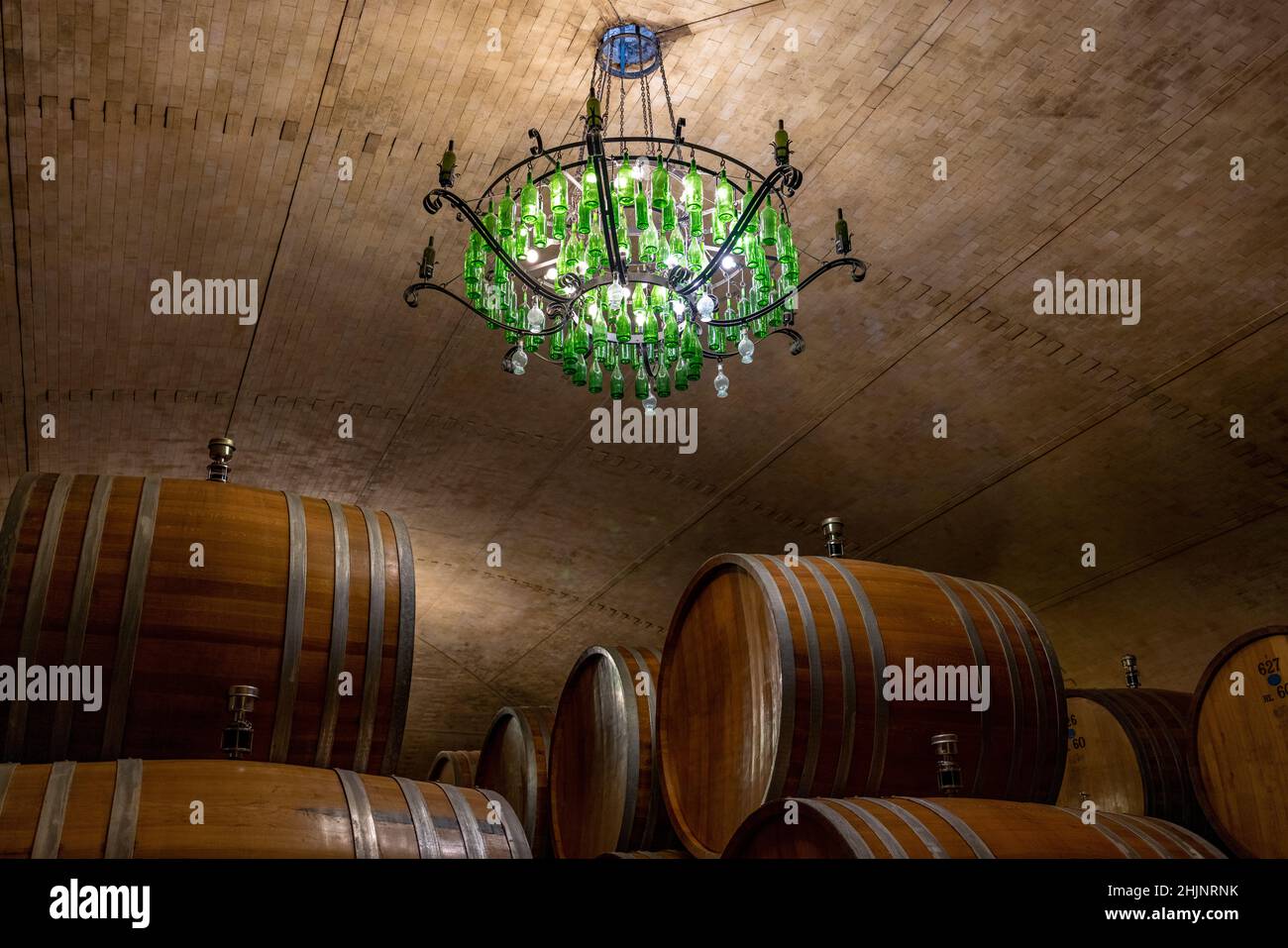 Weinkeller mit großen Fässern und einem grünen Kronleuchter, der von oben hängt Stockfoto