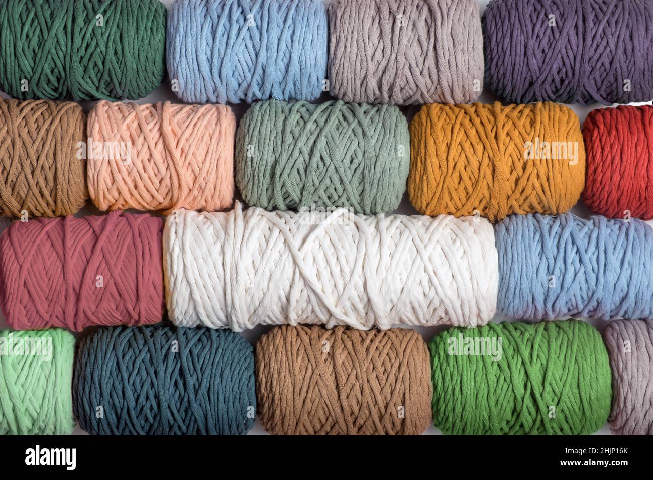 Hintergrund von bunten Macrame Garnen. Textur von natürlichen Baumwoll-Makramgarnrollen. Flach liegend Stockfoto