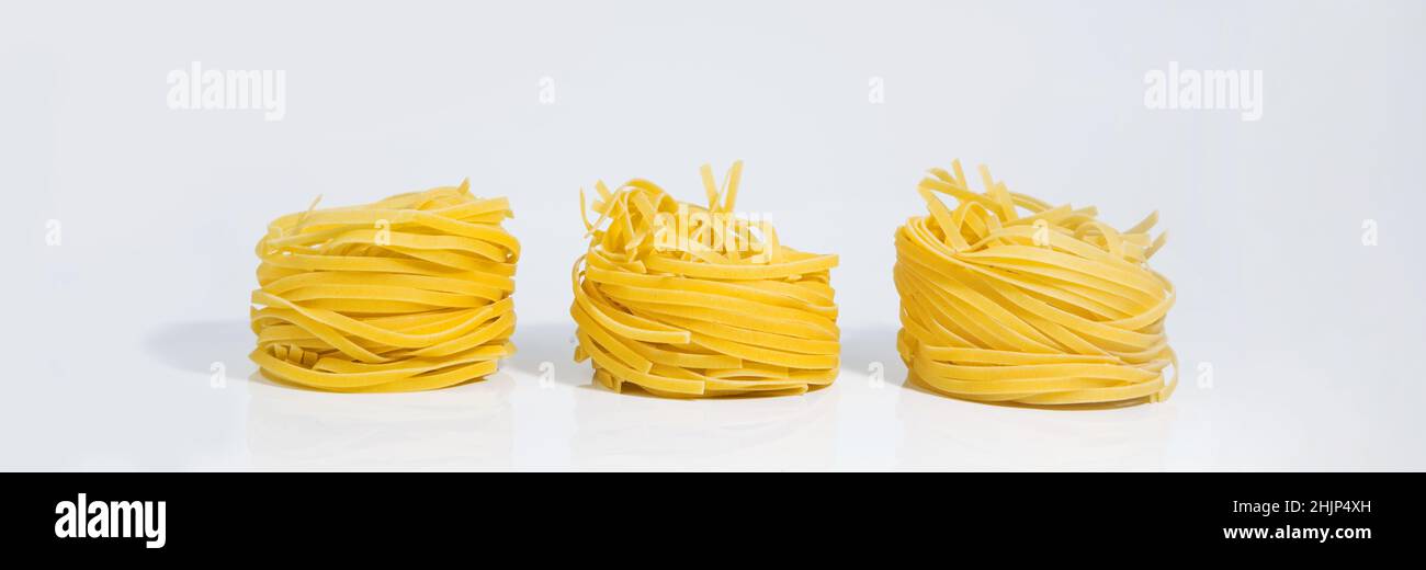 Italienische Pasta. Spaghetti Capellini isoliert auf einem grau-weißen Hintergrund mit harten Schatten. Pasta in Form von Nestern. Kreatives Foto von Pasta. Stockfoto