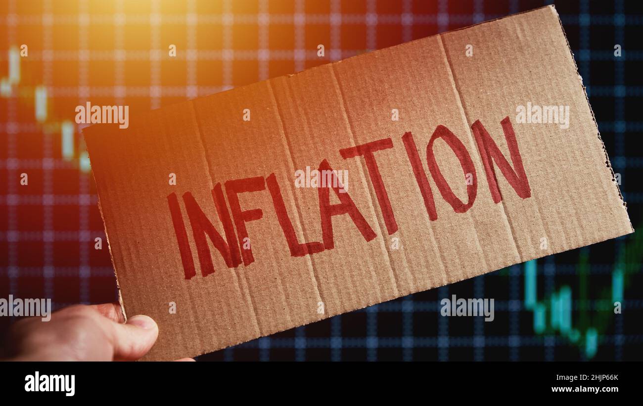 Karton mit Wort Inflation im Hintergrund mit Marktkursdiagramm, Aktienmärkte fallen aufgrund der Inflation Stockfoto
