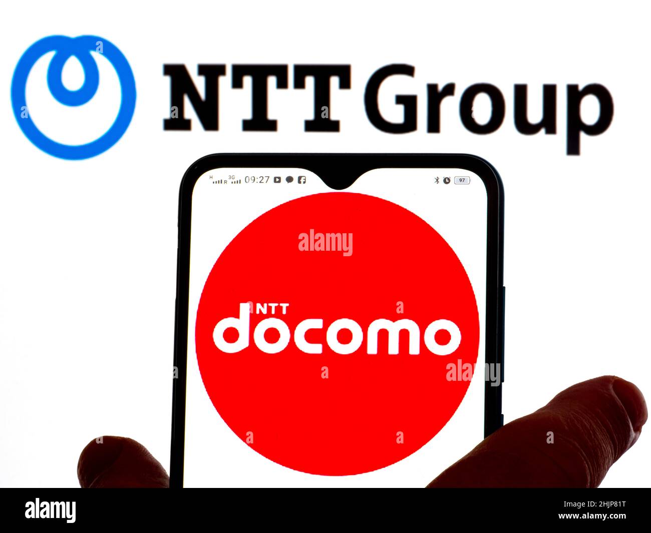 In dieser Abbildung wird das NTT Docomo-Logo auf einem Smartphone-Bildschirm mit dem Logo von Nippon Telegraph and Telephone Corporation im Hintergrund angezeigt. Stockfoto
