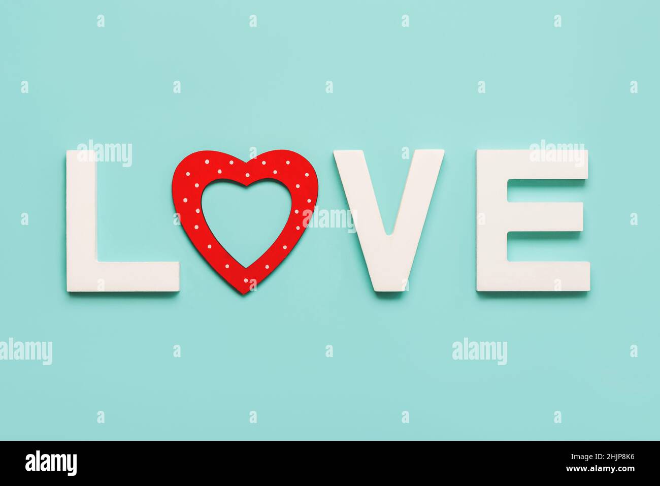 Alles Liebe zum Valentinstag. Das Wort Liebe in weißem Holz mit einem roten Herzen auf blauem Hintergrund. Konzept für die Valentinstag-Feier Stockfoto