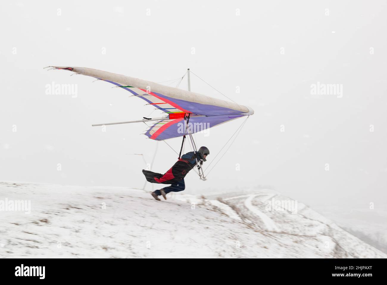 Drachenflieger-Piloten laufen im Winter auf der Piste. Extremsport Stockfoto