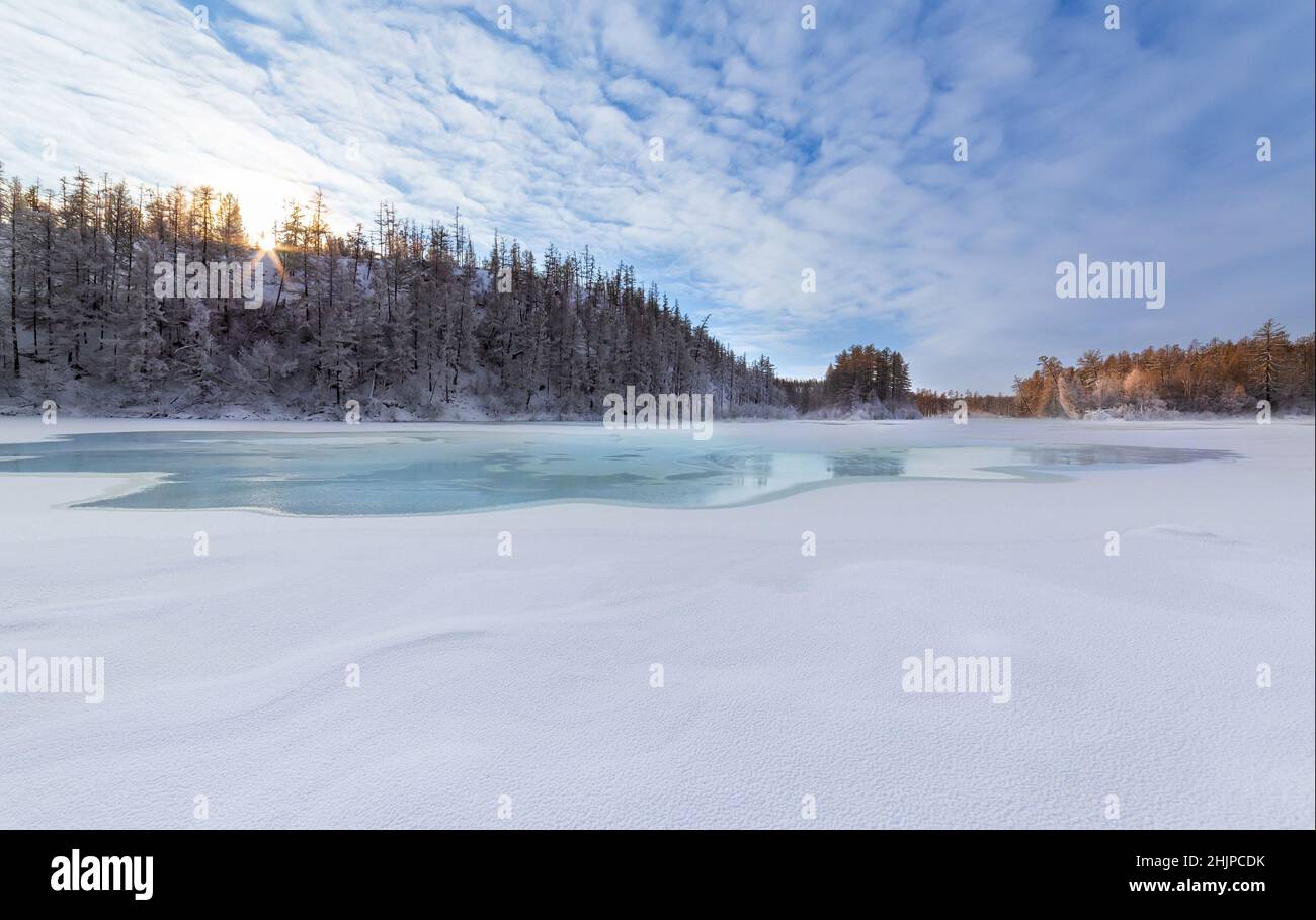 Winterlandschaft am Morgen auf dem Fluss mit türkisfarbenem Eis. Mündung des Flusses der Stadt in Südjakutien, Russland Stockfoto